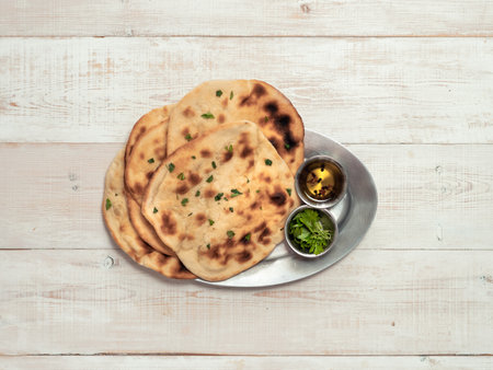 Fresh naan bread on white wooden background with copy space. Top view of several perfect naan flatbreads on metal trayの写真素材
