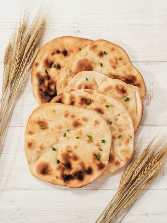 Fresh naan bread on white wooden background with copy space. Top view of several perfect naan flatbreads on metal tray. Verticalの写真素材