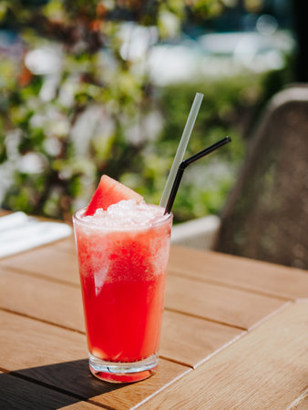 Fresh drink with watermelon, cold summer lemonade, healthy mocktail. Watermelon drink in sunny summer day shadows on wooden table background with copy space. Vertical.の写真素材