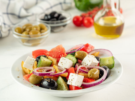 Greek salad on the white table, vertical. Fresh greek salad on plate. High key light. Close up. Selective focus. Copy space. Side viewの写真素材