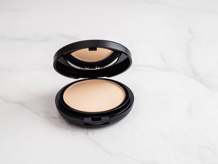 Compact powder on white marble background. Female pressed powder in opened black plastic case with mirror, copy space for text or design.の写真素材