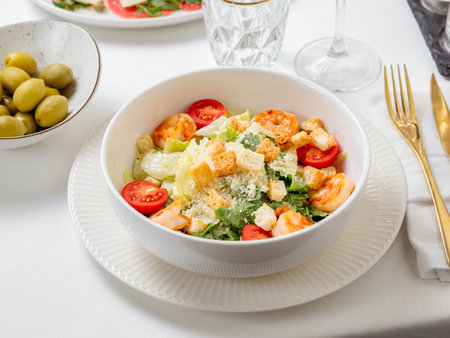 Caesar salad with shrimps on plate in restaurant table interior. Classic caesar shrimp salad closeup viewの写真素材