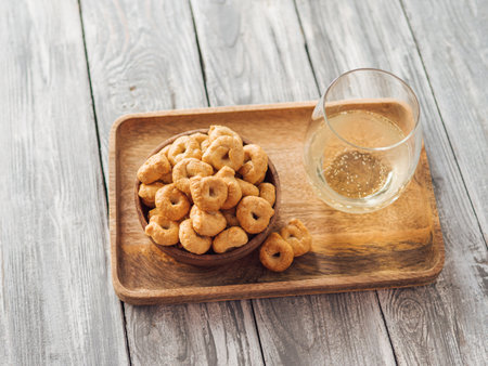 Traditional italian snack taralli or tarallini in wooden bowl and wine glass over wooden tray on old gray wooden background. Rustic shot of taralli appetizer with copy spaceの写真素材