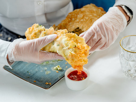 Big fried cheburek with feta cheese, on the restaurant table. Eating cheburek with sauceの写真素材