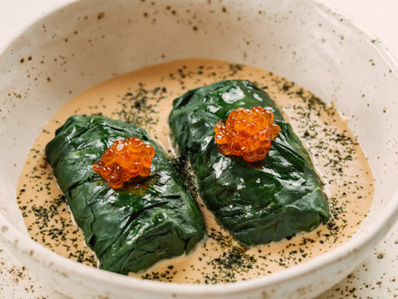 Stuffed green cabbage rolls with sauce in restaurant-style plating, served red caviarの写真素材
