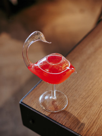 Cosmopolitan cocktail in swan bird glass, minimalistic aesthetic photo on bar counter edge. Popular alcoholic cosmopolitan cocktail made with vodka, triple sec, cranberry juice, lime juice. Bar menuの写真素材