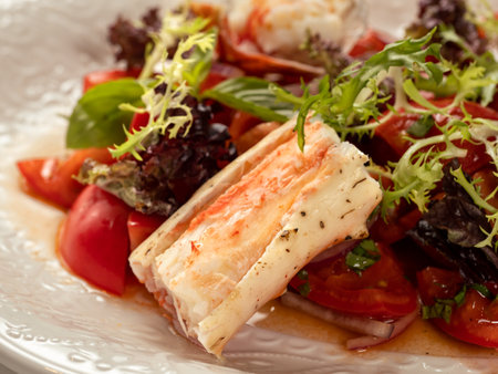 Delicious seafood crab salad on white plate on restaurant table background. Plate with healthy salad made with crab, tomatoes and fresh greens, decorated basil. Close upの写真素材