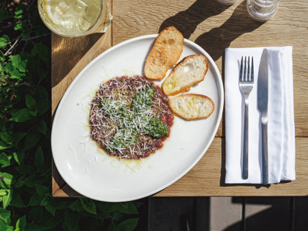 Tuna or beef carpaccio with pesto sauce and parmesan cheese on rustic plate. Antipasti and lunch concept. Delicious food in summer sunny day outdoor of restaurant or cafe terrace. Top view or flat layの写真素材
