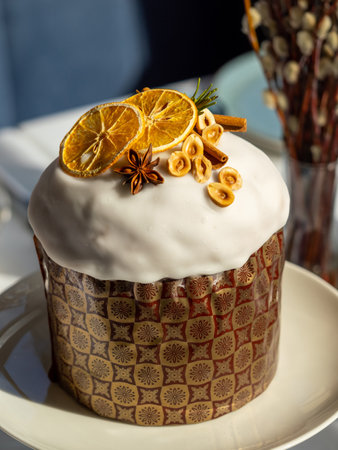 Delicious Easter cake with sugar glaze decorated orange slices, cinnamon and star anise, nuts, close up. Festive orthodox easter cake kulich on the table and willow on backgroundの写真素材