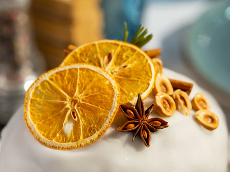 Delicious Easter cake with sugar glaze decorated orange slices, cinnamon and star anise, nuts, close up. Festive orthodox easter cake kulich on the table and willow on backgroundの写真素材