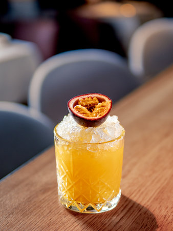 Yellow old-fashioned refreshing cocktail with whiskey and crushed ice on bar counter. Vertical. Alcohol or non-alcohol cold cocktail decorated passion fruit. Copy space.の写真素材