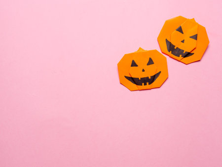 Halloween concept. Paper origami pumpkin on pink background. Simple idea for halloween - easy made paper pumpkins on trendy color Ceylon Yellow background. Copy space for text.の写真素材