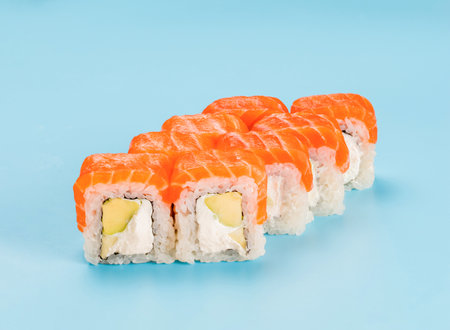 Studio photography of Philadelphia Roll of velvety cream cheese, and avocado, wrapped in perfect seasoned sushi rice and fresh salmon. Isolated on solid light blue backgroundの写真素材