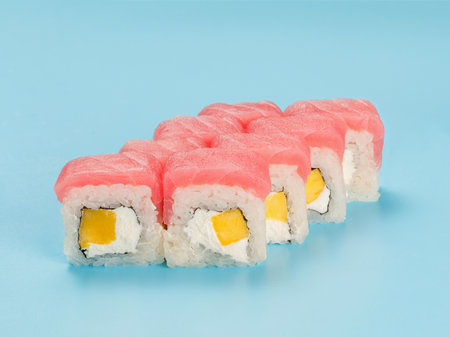 Studio photography of Philadelphia Roll of velvety cream cheese and mango wrapped in perfect seasoned sushi rice and fresh tuna. Isolated on solid light blue backgroundの写真素材