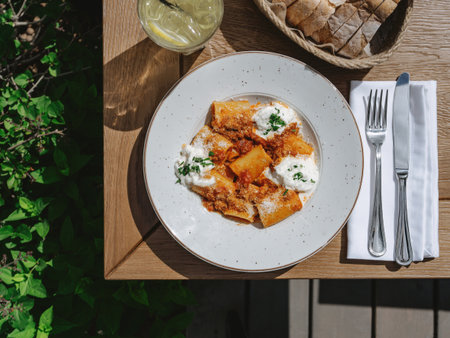 Tortiglioni bolognese pasta or paccheri bolognese in plate. Tasty food in summer sunny day outdoor...