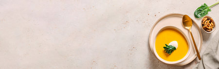 Pumpkin cream-soup served spinach, nuts, sour cream. Banner. Tasty Homemade Pumpkin, Sweet Potato or Carrot Soup in Bowl on Neutral Pastel Background. Cozy autumn comfort food. Copy space. Top viewの写真素材