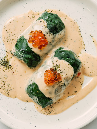 Stuffed green cabbage rolls with sauce in restaurant-style plating, served red caviar
