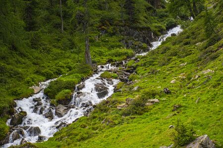 streams from the Otztal valley in south Tyrol in the Austrian Alps near Solden on a cloudy day but with real meadows and gray rocksの写真素材