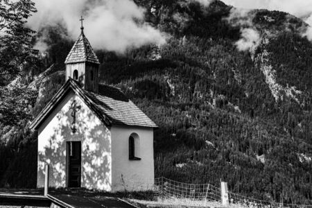 Alpine church surrounded by green meadows and very high mountains in the otztal valley in the Austrian Alps of Tyrol on a cloudy summer dayの写真素材