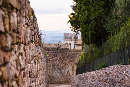 path set between centuries-old stone walls in the beautiful Assisi in Italyの写真素材