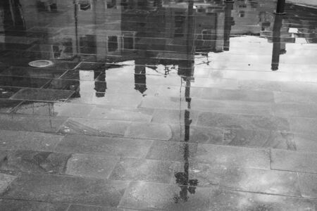 reflections of the buildings of Mestre Venice on the sidewalk wet by a summer stormの写真素材