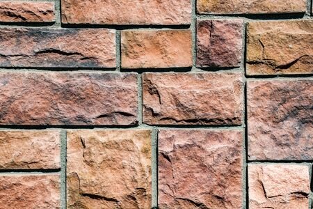 photo of a wall of reddish stone bricks bound by gray cement