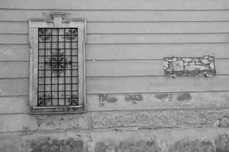 closed window with wooden shutters and rusty flower-shaped grating and on the wall the place of a plaqueの写真素材
