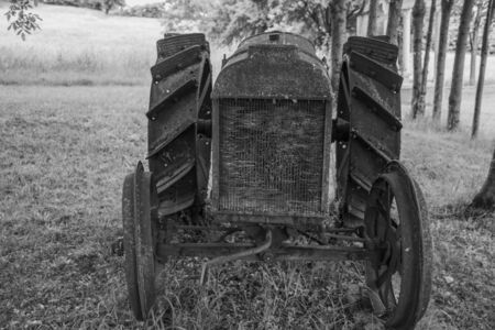 closeup of an old rusty tractor disused and abandoned among the trees in the meadows of the Bregonze hills near Thiene, Vicenza, Italyの写真素材