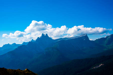 Blue sky with white clouds surround the pink peaks of the Cortina D'ampezzo Dolomites in Belluno,...