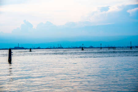 the industrial area of Marghera against the backdrop of a still lagoon in a summer twilight in Venice, Italyの写真素材