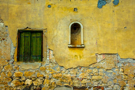 old window closed by old wooden shutters on stone wall in Castegnero, Vicenza, Veneto, Italy