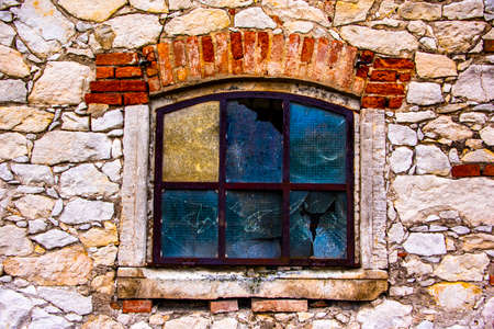 vintage window of an old barn with broken glass and rusty railing