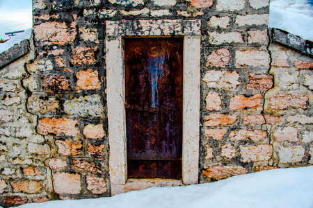 small rusty door with writing and stone wallの写真素材