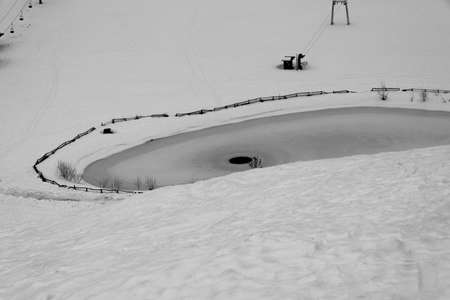 small alpine lake frozen and immersed in the snow on a foggy winter dayの写真素材