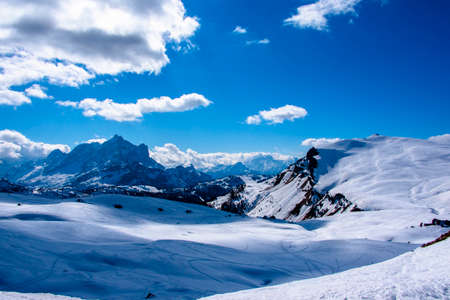 peaks of the Dolomites with snow, alpine valleys blue sky white clouds, snow tracks in the Zoldo valley, Belluno, Italyの写真素材