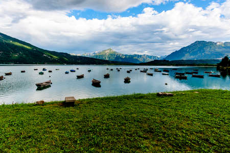old wooden fishing boats moored on the lake that is reflected in the dolomites of lake Santa Croce...