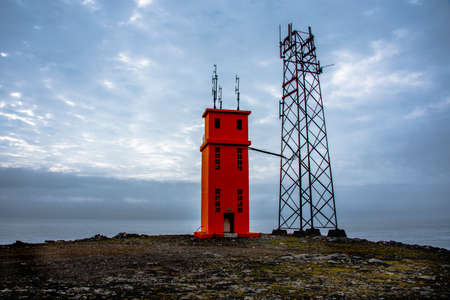 orange lighthouse with communications pylon on the cliffs of Hvalnes in icelandの写真素材