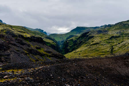 the Skogafoss waterfalls in summer with the green of the mountains and the pouring water near Vik in Icelandの写真素材