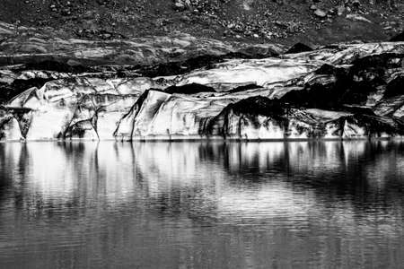 Solheimajokull glacier covered in soot from previous eruptions with the glacial lake descending from the volcano near Vik in Icelandの写真素材