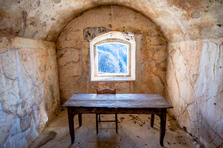 abandoned room of the first world war with old wooden table and chair with window on the rocks of...