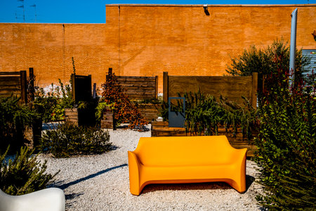 orange plastic sofa on botanical garden with brick wall and blue sky tranquility landscape architectureの写真素材