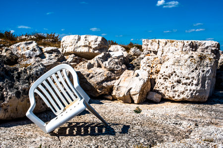 old broken white plastic chair on abandoned rocks in Croatian islandsの写真素材