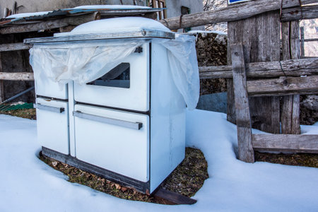 old abandoned stove outside a log cabin in the snow in Recoaro Vicenza Veneto Italyの写真素材