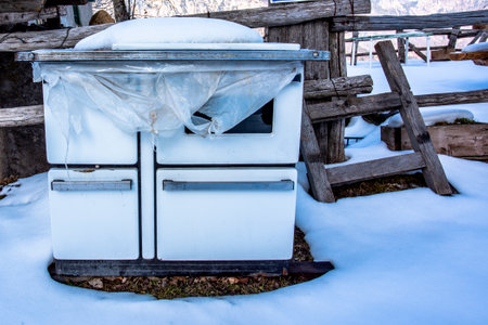 old abandoned stove outside a log cabin in the snow in Recoaro Vicenza Veneto Italyの写真素材