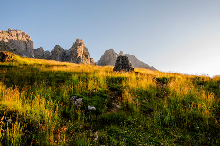 Dolomite mountains and Alps peaks with green meadows and rock spiers among woods and alpine pastures...