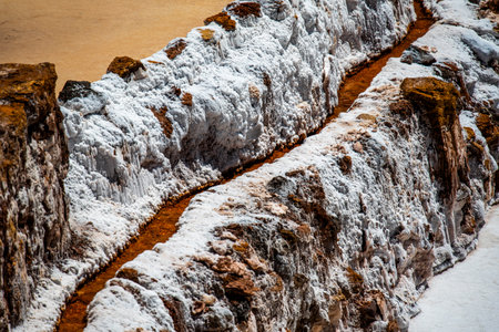 detail of the mountain salt pans with the white of the salt and the brown of the water which is...