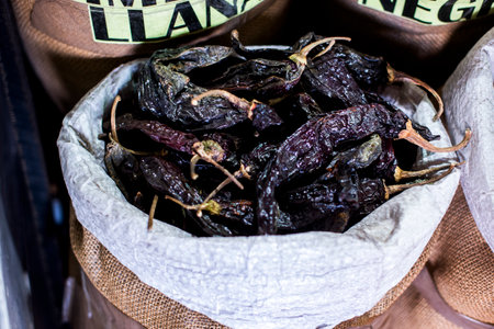 detail of red and black dried allspice or cherry pepper on baskets in a market in Cusco in Peru in...