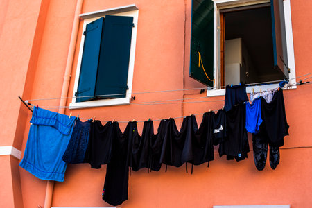 laundry hanging out in the autumn sun in the town of Pellestrina on the Venice Lagoon black t-shirts hanging on a brick-coloured wallの写真素材