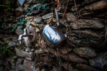 old chrome iron mug hanging from an old mountain fountain
