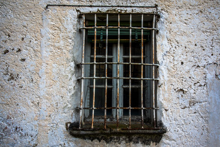 old window with rusty grate wall of an old country house closed by iron grateの写真素材
